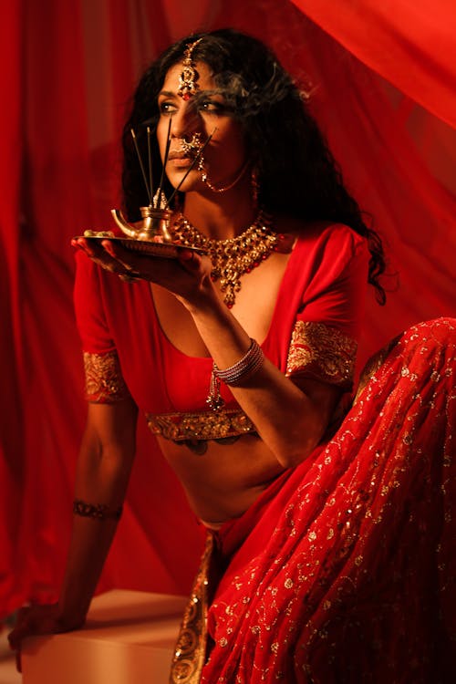 Woman in Red Dress Holding a Plate with Lighted Incense Stick