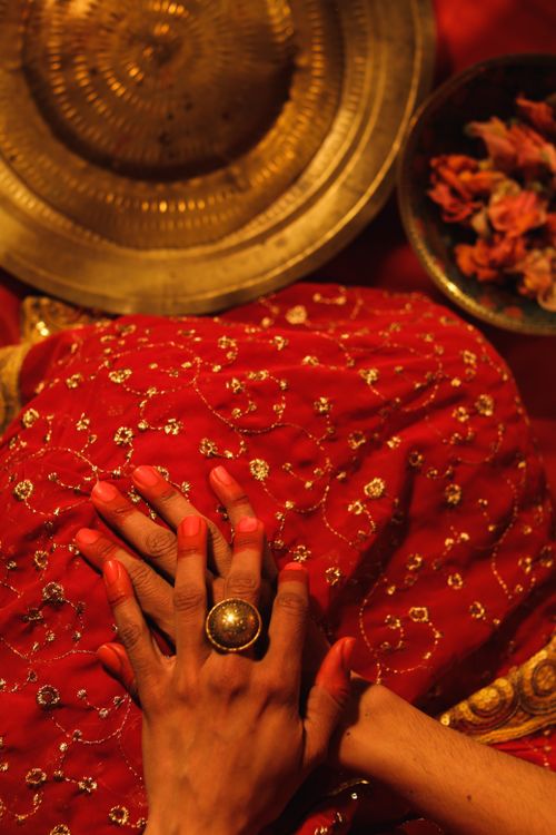 Free Hands adorned with henna over a detailed red fabric with traditional gold plate. Stock Photo