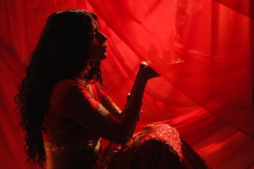 A Woman in Red Traditional Dress Looking at the Plate she is Holding