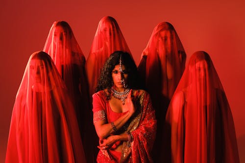 Woman in Sari among Women in Red Veils