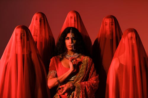 Brunette in Sari among Women in Red Veils