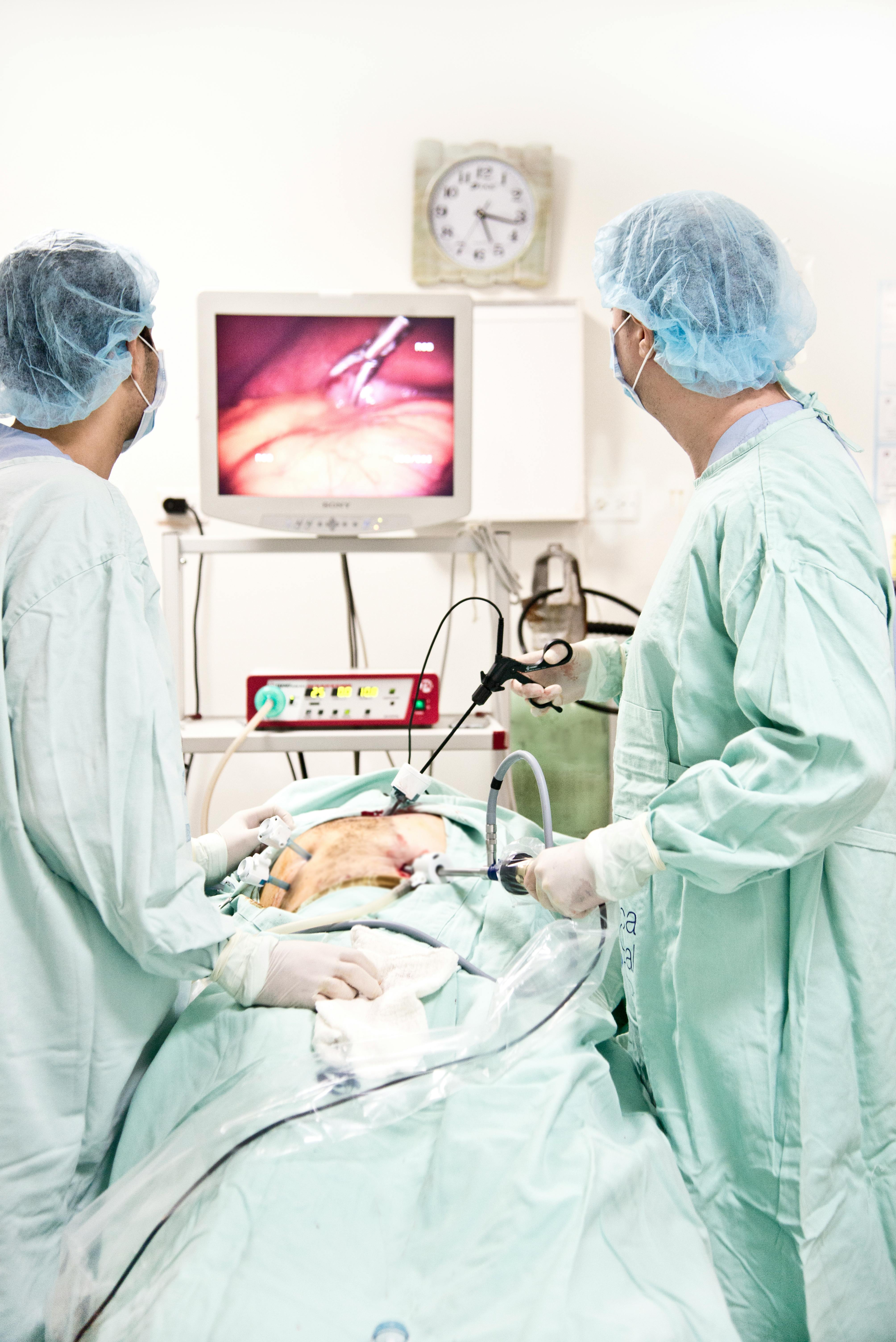 woman in white scrub suit standing near baby lying on hospital bed