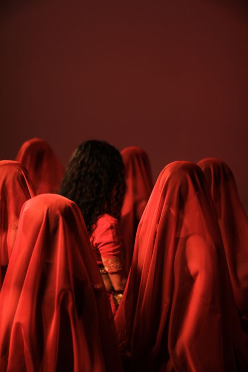 Editorial portrait of women in red veils shot at 50mm, showing the context a 50mm keeps in 50mm vs 85mm portraits