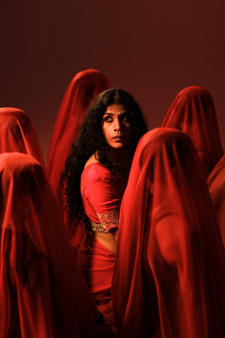 A Woman In Red Shirt Standing Between The People Wearing Headscarves