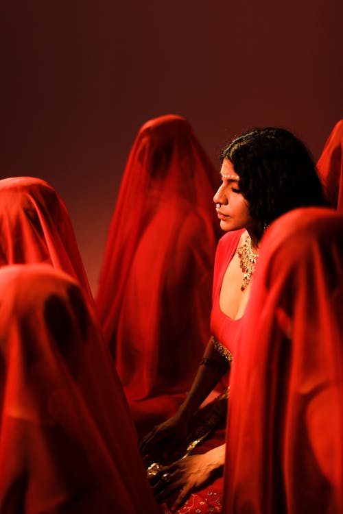 Brunette Meditating among Women in Red Veils