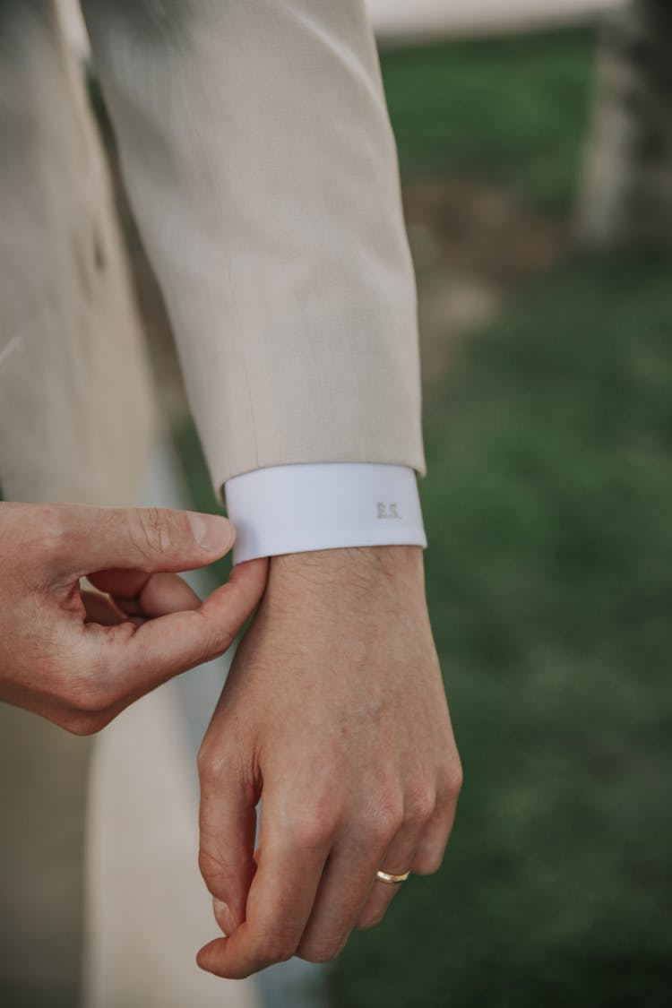 A Person's Hand Fixing The Cuff Of His Shirt