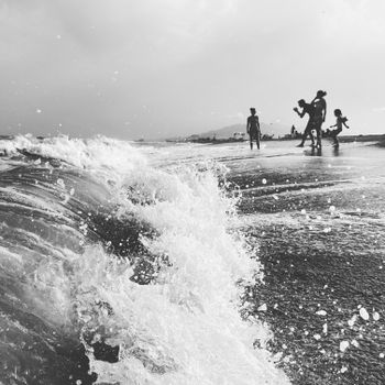 Grayscale image of people enjoying waves at Vera Beach, Spain.