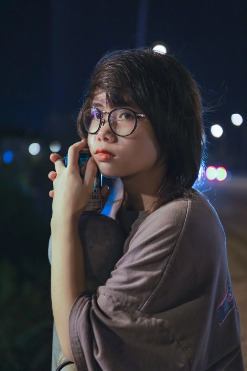 Free Young woman with glasses holding a can outdoors at night, exuding a thoughtful mood. Stock Photo