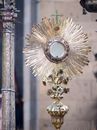 Beautifully adorned golden monstrance in shape of sunburst during Catholic procession in street
