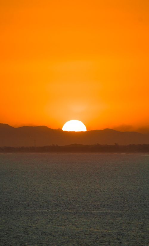 Free Dramatic sunset over Arraial do Cabo with orange sky and mountains silhouette. Stock Photo