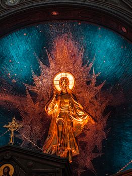 A golden statue of Jesus Christ with a radiant backdrop inside a church, illustrating religious art.