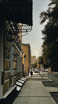 A calm city street in Moscow, Russia, lined with historic buildings and autumn trees.