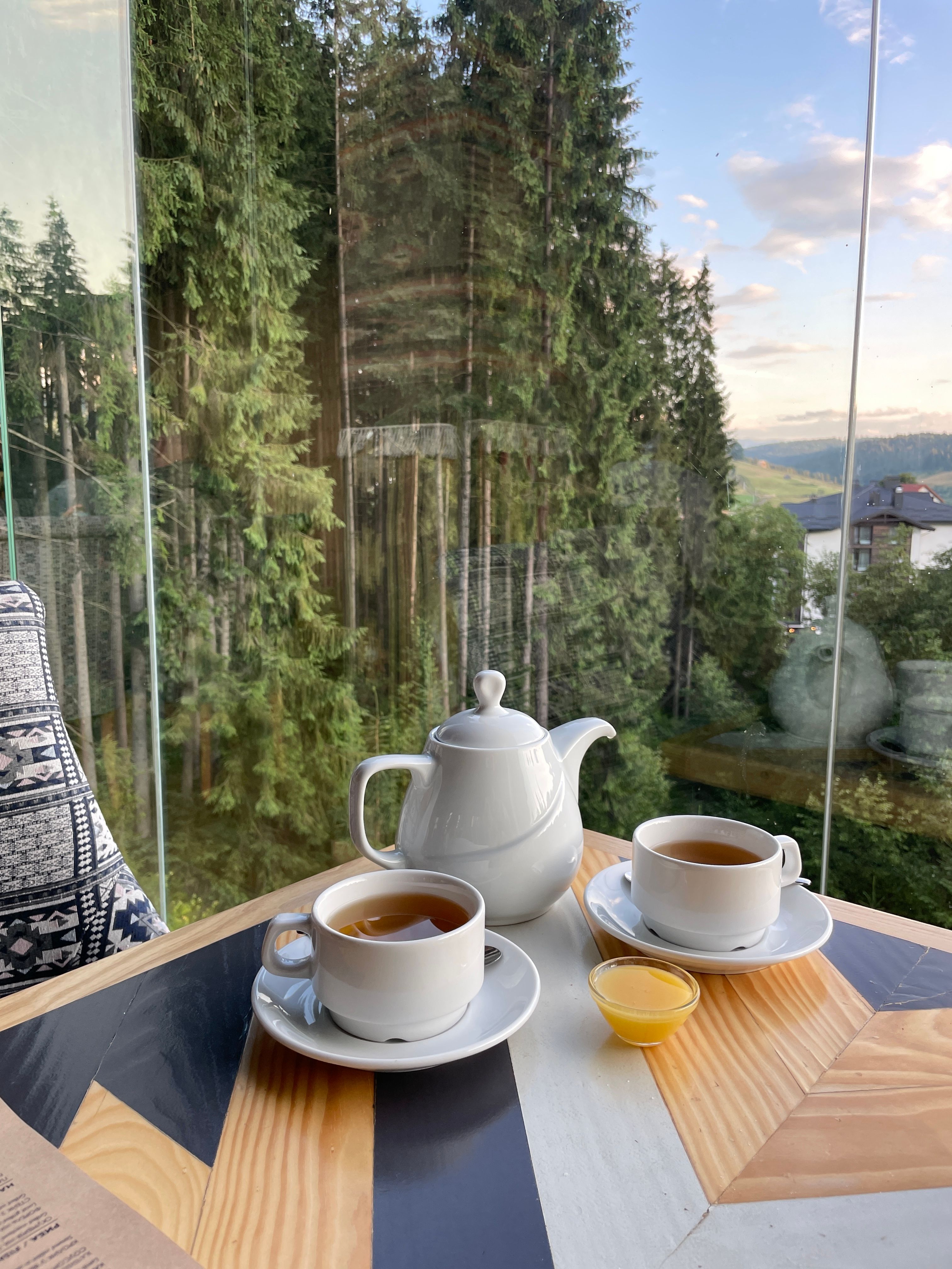 Enjoy a serene tea time overlooking the lush forests of Bukovel, Ukraine. Perfect for relaxation.