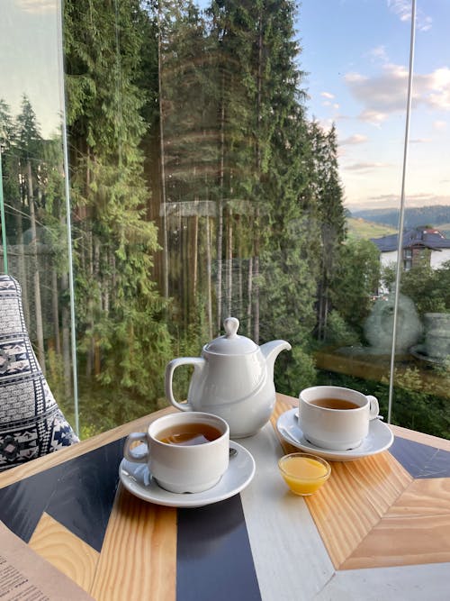 A Teapot and Cups of Tea on a Wooden Table