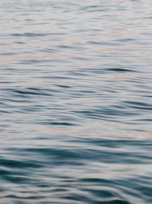 Free A serene view of gentle ripples on water, capturing the peaceful ambiance at dusk. Stock Photo