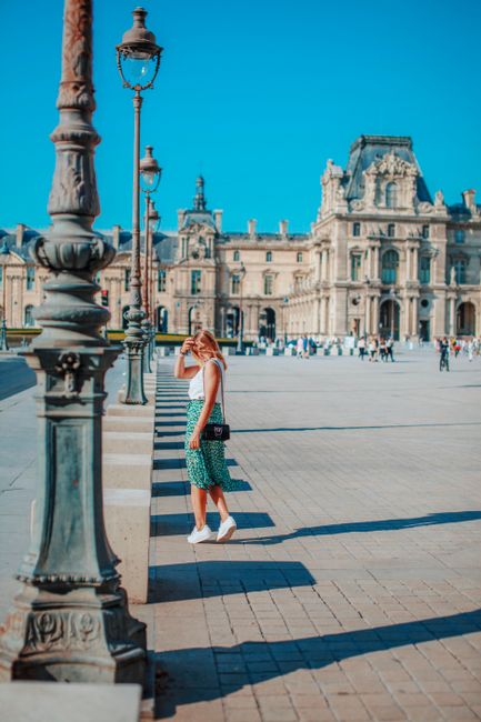 Fotomural Mujer a la moda posando frente al Museo del Louvre en verano, París. Monumento icónico con arquitectura histórica.