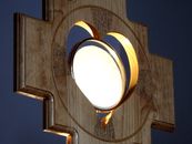 Wooden cross shaped monstrance with lit up Communion bread in heart shaped center against dark blue background