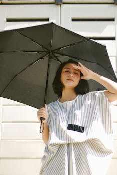 A woman holds an umbrella to shield herself from bright sunlight. Stylish summer dress.