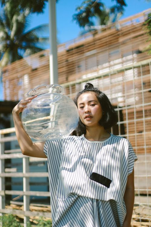 Free A woman with short hair in a striped dress holding a glass jar outdoors. Stock Photo