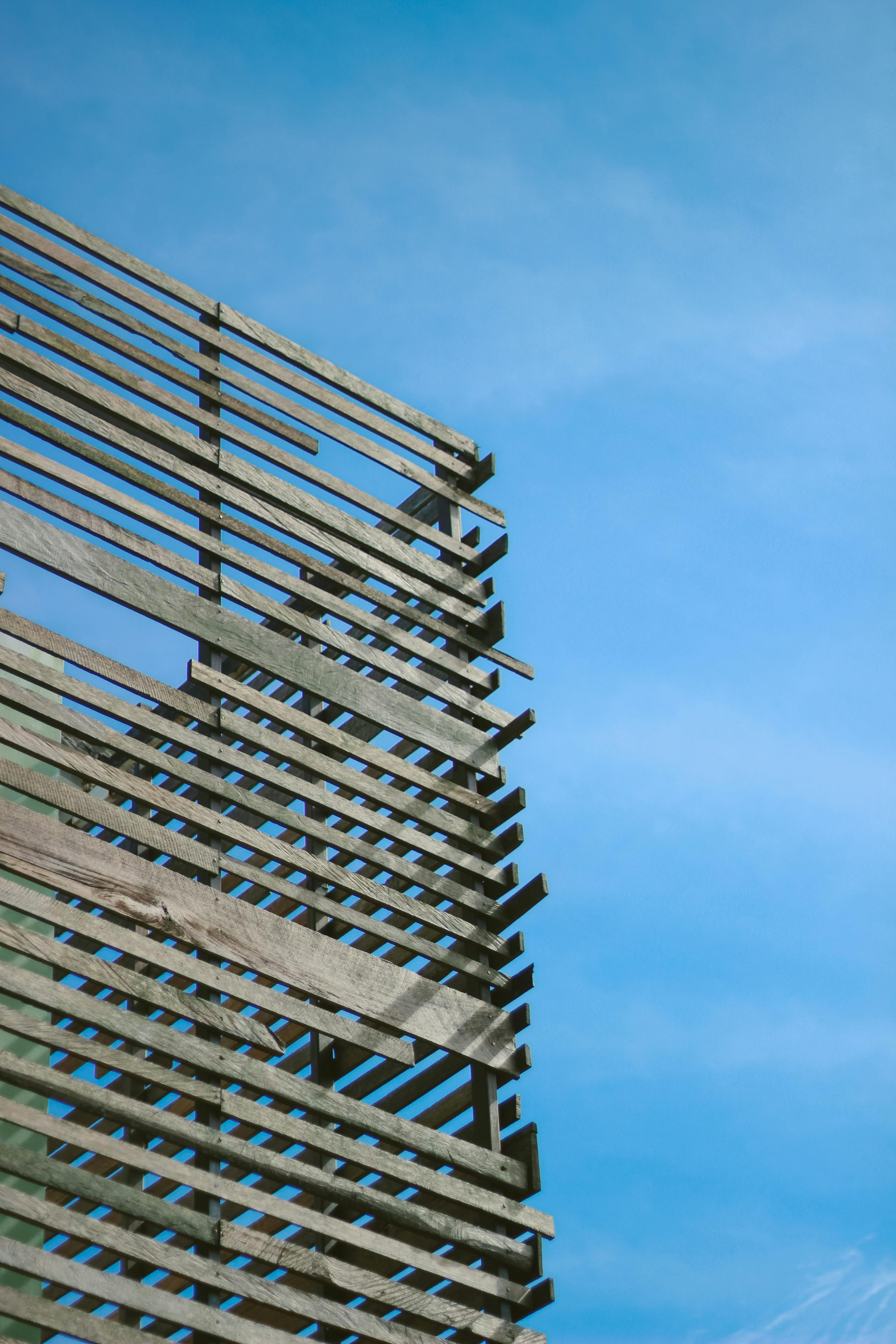 Minimalist wooden slat architecture contrasting with a clear blue sky, emphasizing modern design.