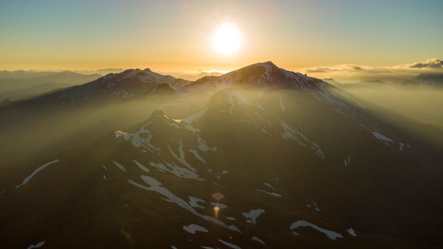 Captivating sunrise illuminating the snow-covered peaks with misty light.