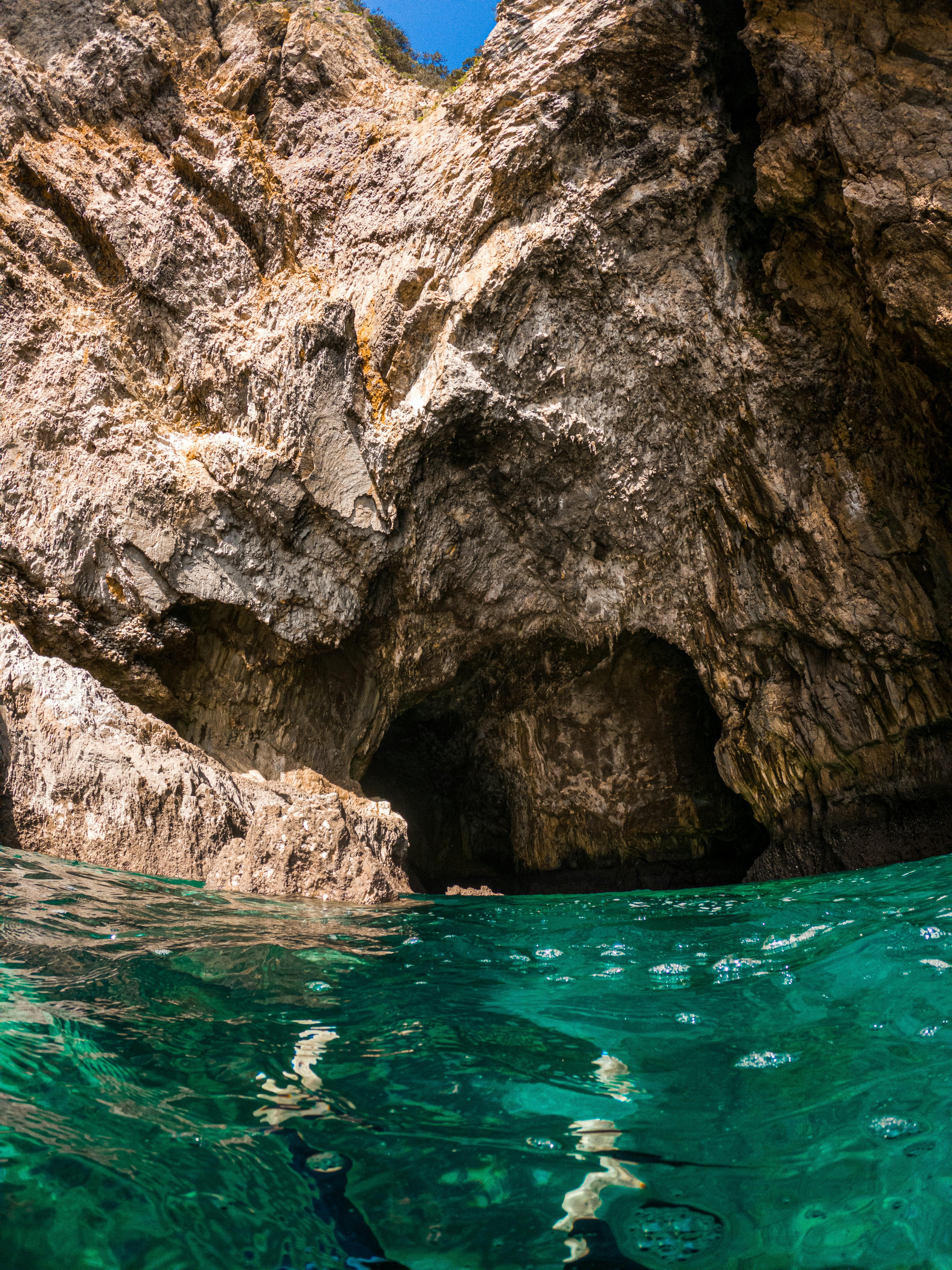 Explore the majestic cliffside cave entrance with vibrant turquoise waters in Santoña, Spain.