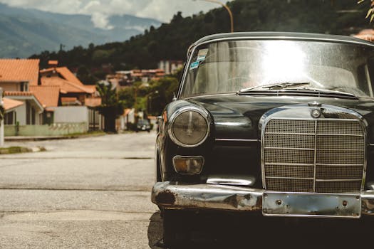 Classic Mercedes Benz parked on a vibrant street in Venezuela with mountain backdrop.