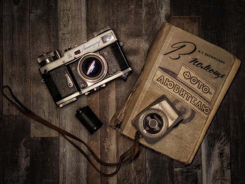 Free Vintage Camera and a Book on Wooden Surface Stock Photo