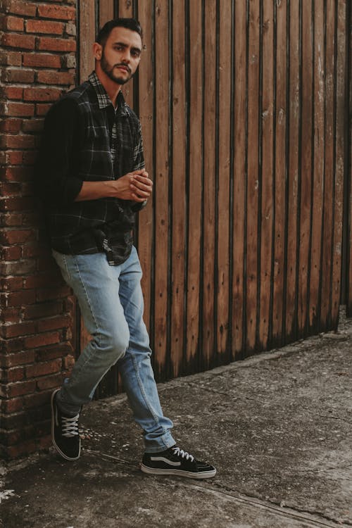 A Man Standing while Leaning on a Brick Wall