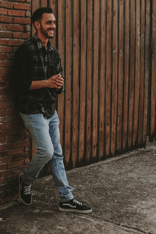 A Man Smiling while Leaning on a Brick Wall