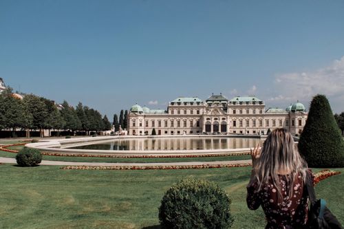 Free Visitor admiring the historic Belvedere Palace in Vienna under clear blue sky with elegant garden setting. Stock Photo