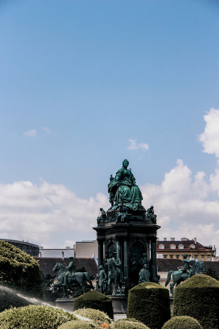 Bronze Statues With Green Patina And Topiary In A Park