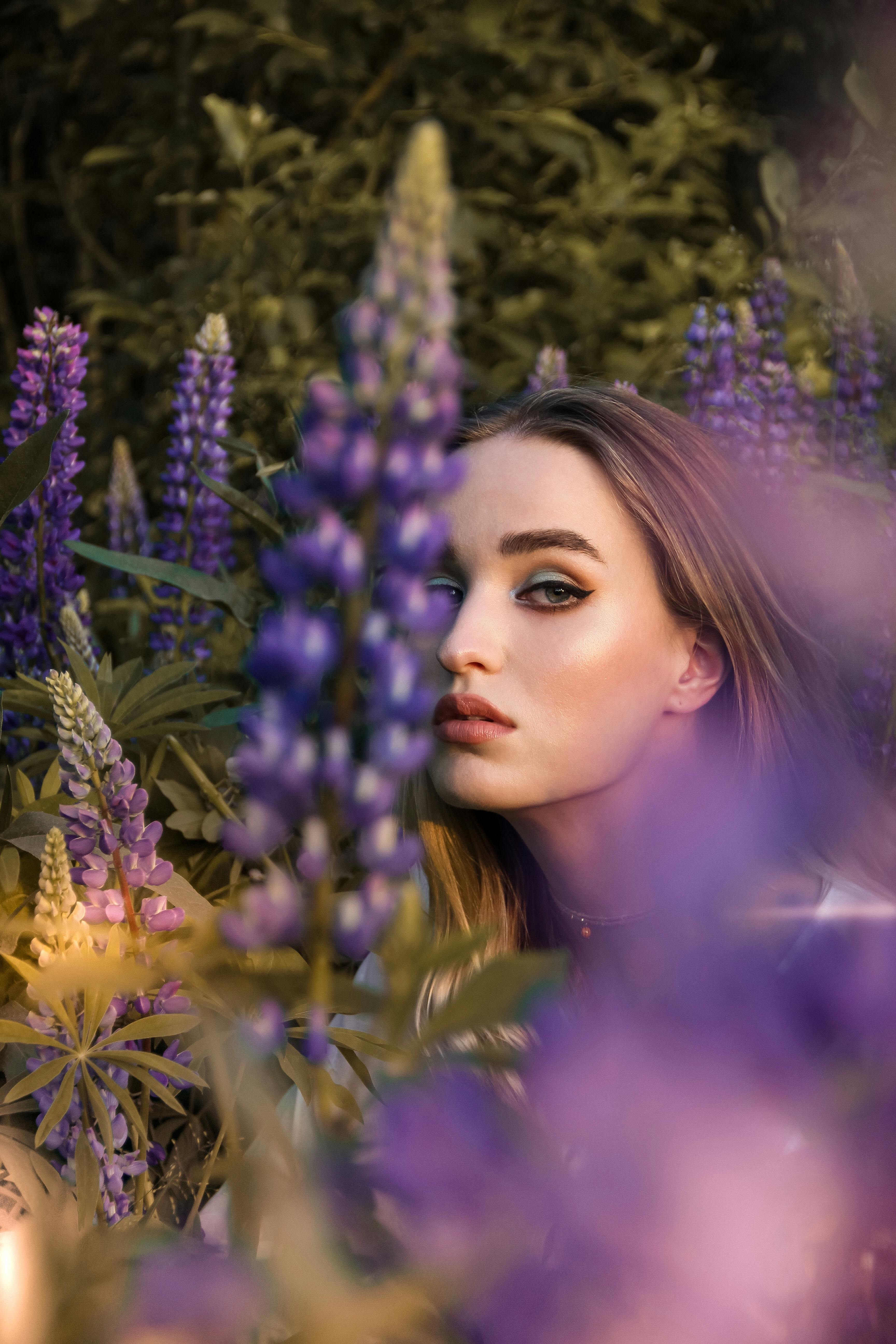 Beautiful portrait of a woman surrounded by vibrant purple lupines, capturing a mystical and serene mood.