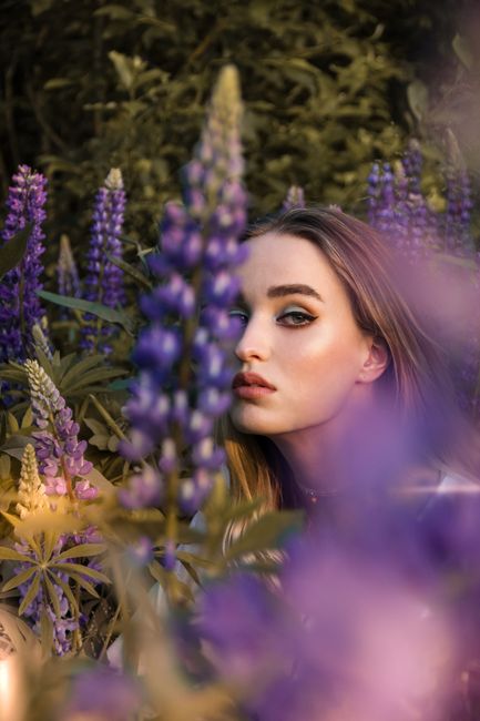 Beautiful portrait of a woman surrounded by vibrant purple lupines, capturing a mystical and serene mood.