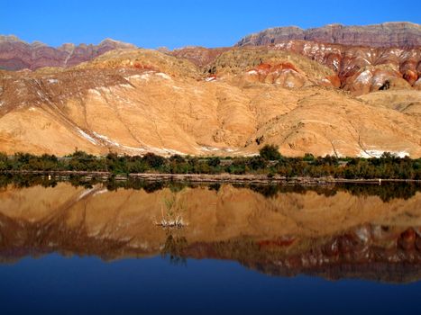Vibrant canyon landscape beautifully reflected in a calm lake, showcasing nature's symmetry.