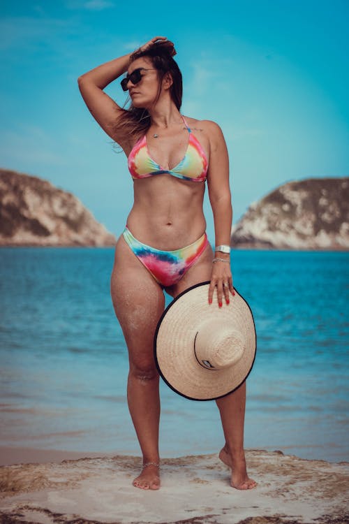 A Woman Wearing a Bikini while Holding a Hat