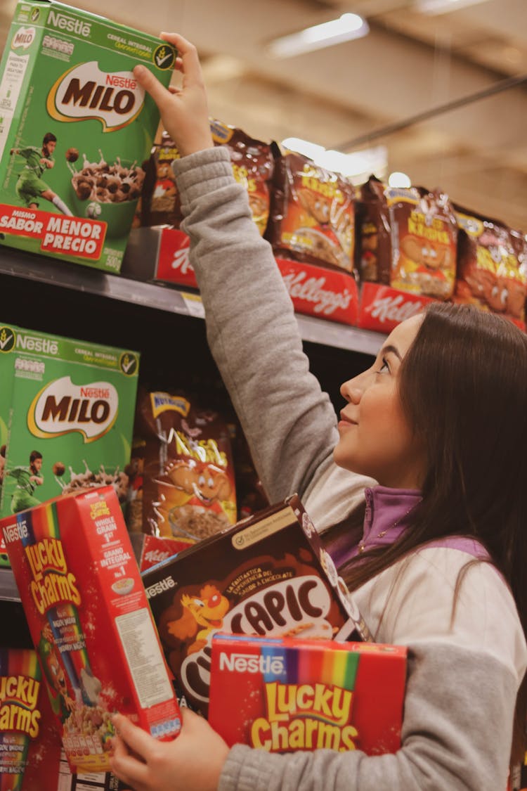 A Woman Getting Cereal Boxes From The Shelf