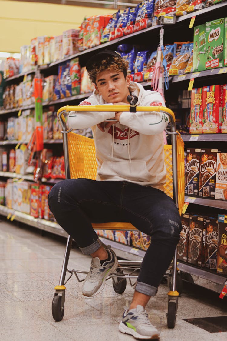 A Man Sitting On A Grocery Cart 