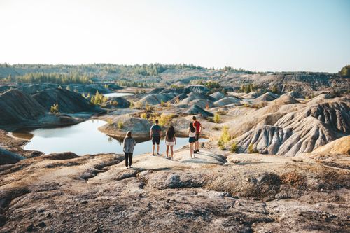 Free Five people hike through a scenic, sunlit eroded landscape with textured rock formations. Stock Photo