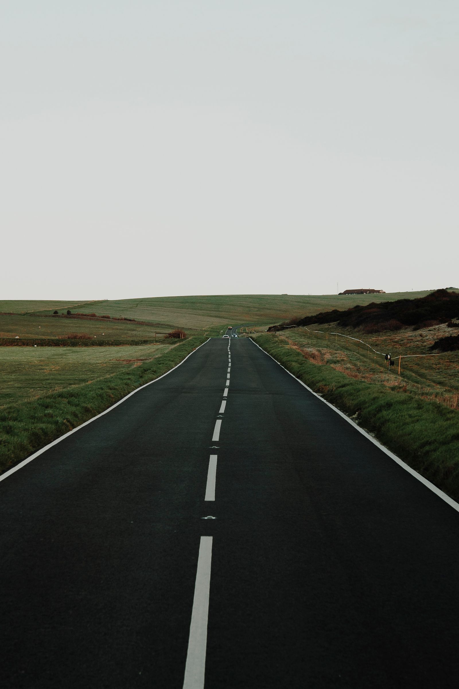 A straight two-lane highway running through open Nebraska farmland under a blue sky
