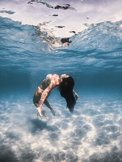 A Woman Swimming Underwater while Wearing a Bikini