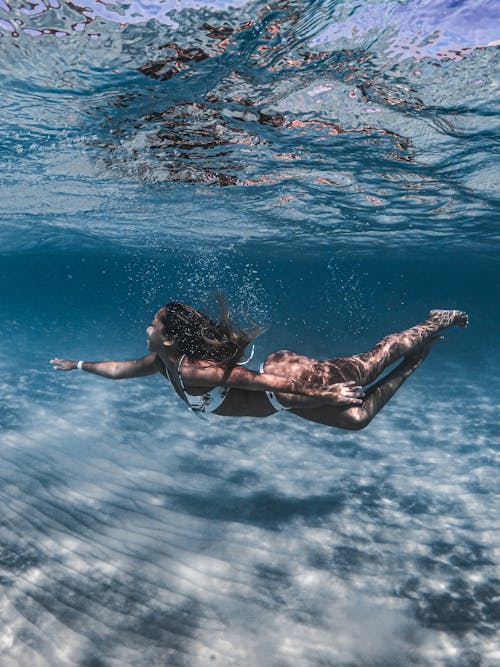 A Woman Swimming Underwater while Wearing Bikini