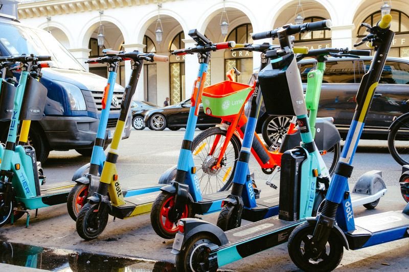 A vibrant collection of electric scooters and bicycles parked on a bustling city street.