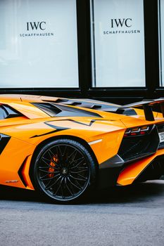 Close-up of an orange Lamborghini Aventador parked on pavement, highlighting luxury design.