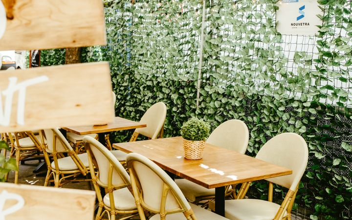 Cozy outdoor restaurant setup with wooden furniture and lush green decor, perfect for dining.