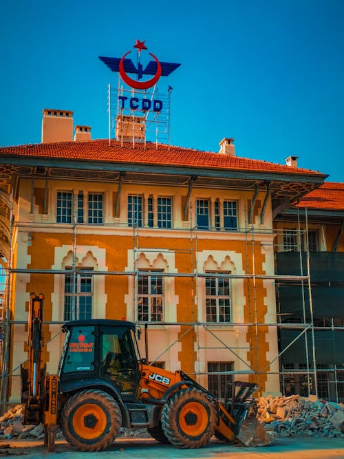 Free Excavator on a Construction Site in Front of a Building  Stock Photo