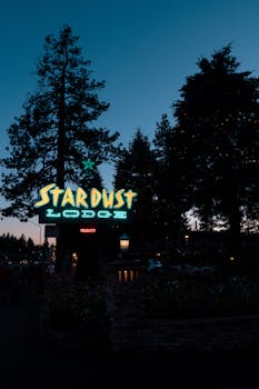 A vibrant neon sign of Stardust Lodge glowing against a twilight sky in Tahoe City, CA.