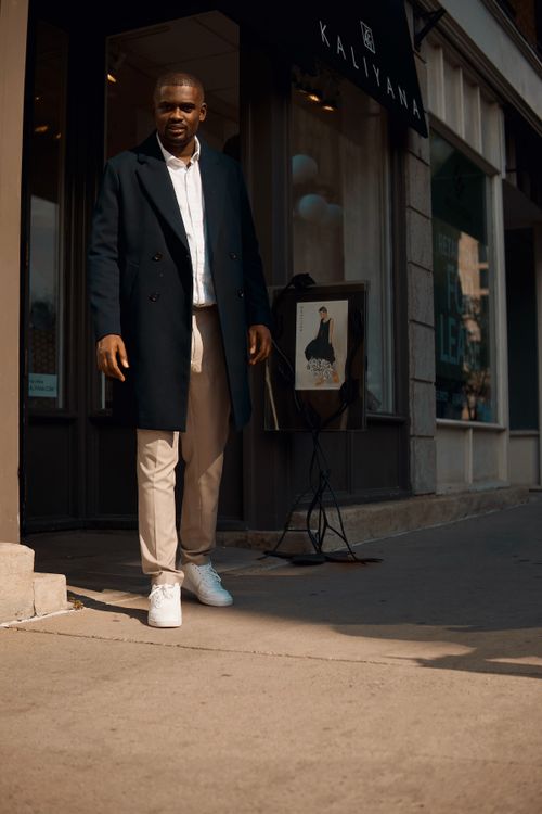 Free Fashionable man in Ottawa wearing a trench coat, standing outside a boutique on a sunny day. Stock Photo