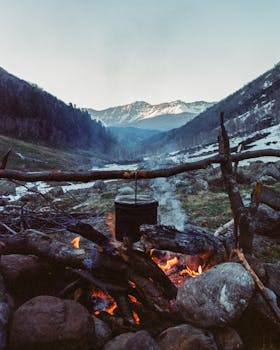 A cozy campfire in a rocky valley with mountains in the background, perfect for camping inspiration.