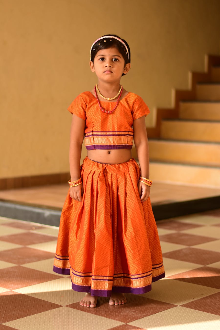 Little girl standing on steps wearing a layered orange skirt set